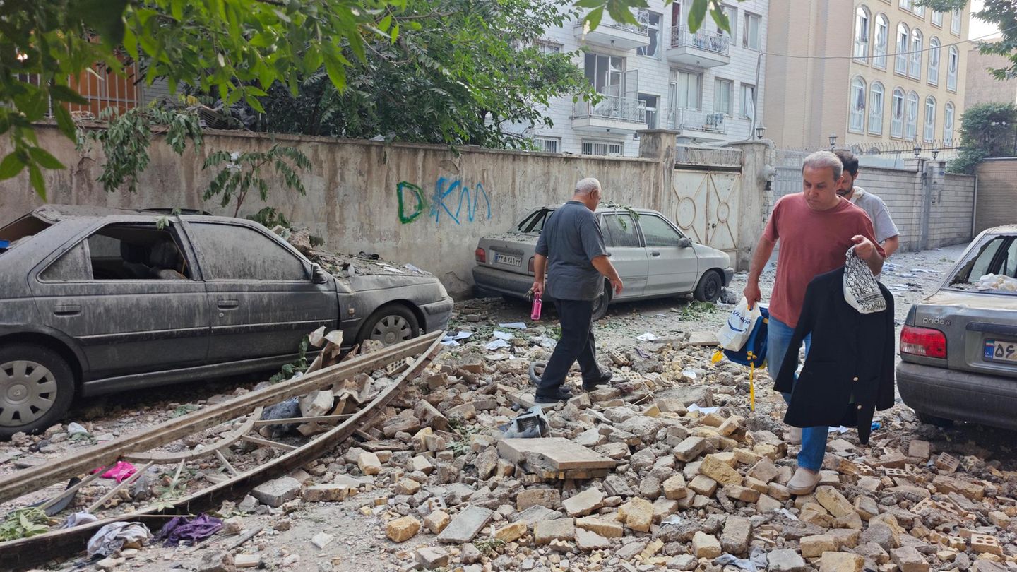 Menschen in Teheran gehen durch Schutt und Trümmer