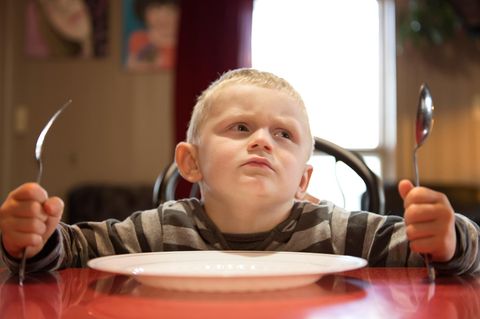 Kinder: Ein Junge sitzt vor einem leeren Teller