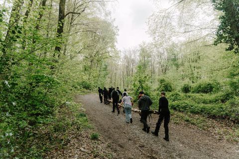 Jugendliche tragen gemeinsam einen Baumstamm durch den Wald – sie absolvieren Sozialstunden