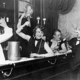 Gäste an der Theke einer Bar stoßen mit Sekt an.