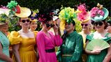 EInen gruppe von Frauen in bunten Kleidern und farbenfrohen Hüten mit Federn beim Royal Ascot