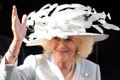 Königin Camilla winkt mit einem Hut auf dem Kopf
