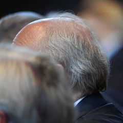 Der grauhaarige Kopf eines Rentners ist in einer Menge zu sehen