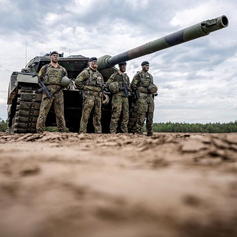 Soldaten stehen vor einem Leopard-2-Panzer der Bundeswehr, der von der Nato eingesetzt wird