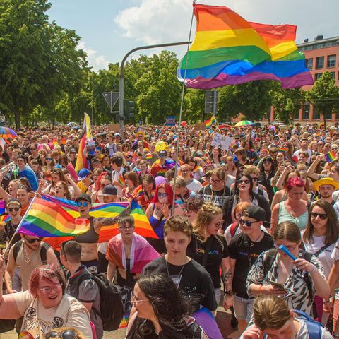 A group of people on a pride parade with rainbow flags