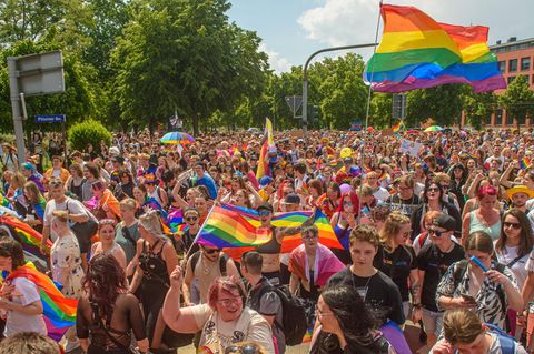 Einen Menschengruppe bei einer Pride-Parade mit regenbogenflaggen