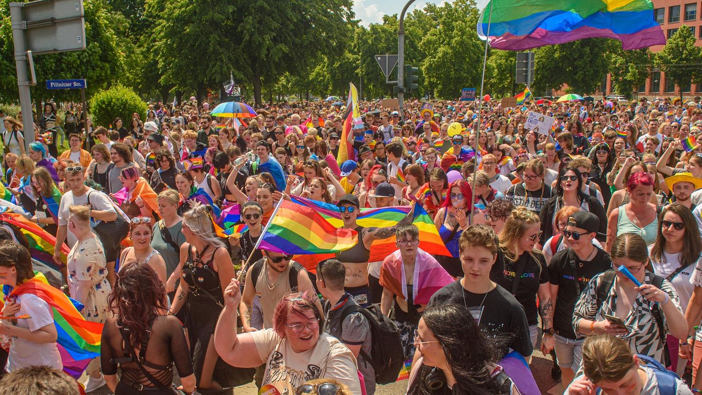 Einen Menschengruppe bei einer Pride-Parade mit regenbogenflaggen