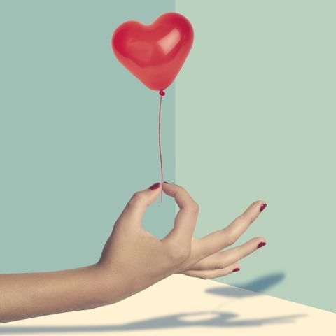 Eine Hand hält einen kleinen Herz-Luftballon