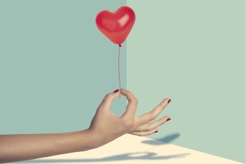 Eine Hand hält einen kleinen Herz-Luftballon