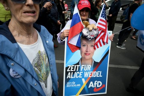 AfD-Anhängerin mit Flaggen der USA und Russlands
