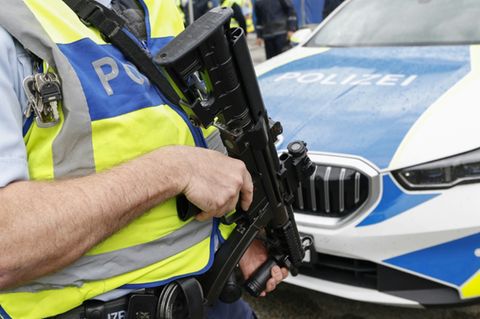 Bewaffneter Polizist vor Streifenwagen
