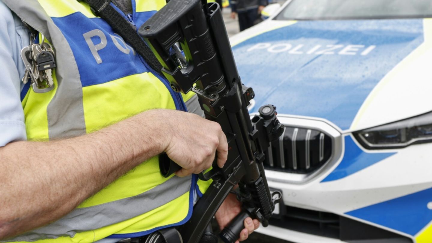Bewaffneter Polizist vor Streifenwagen