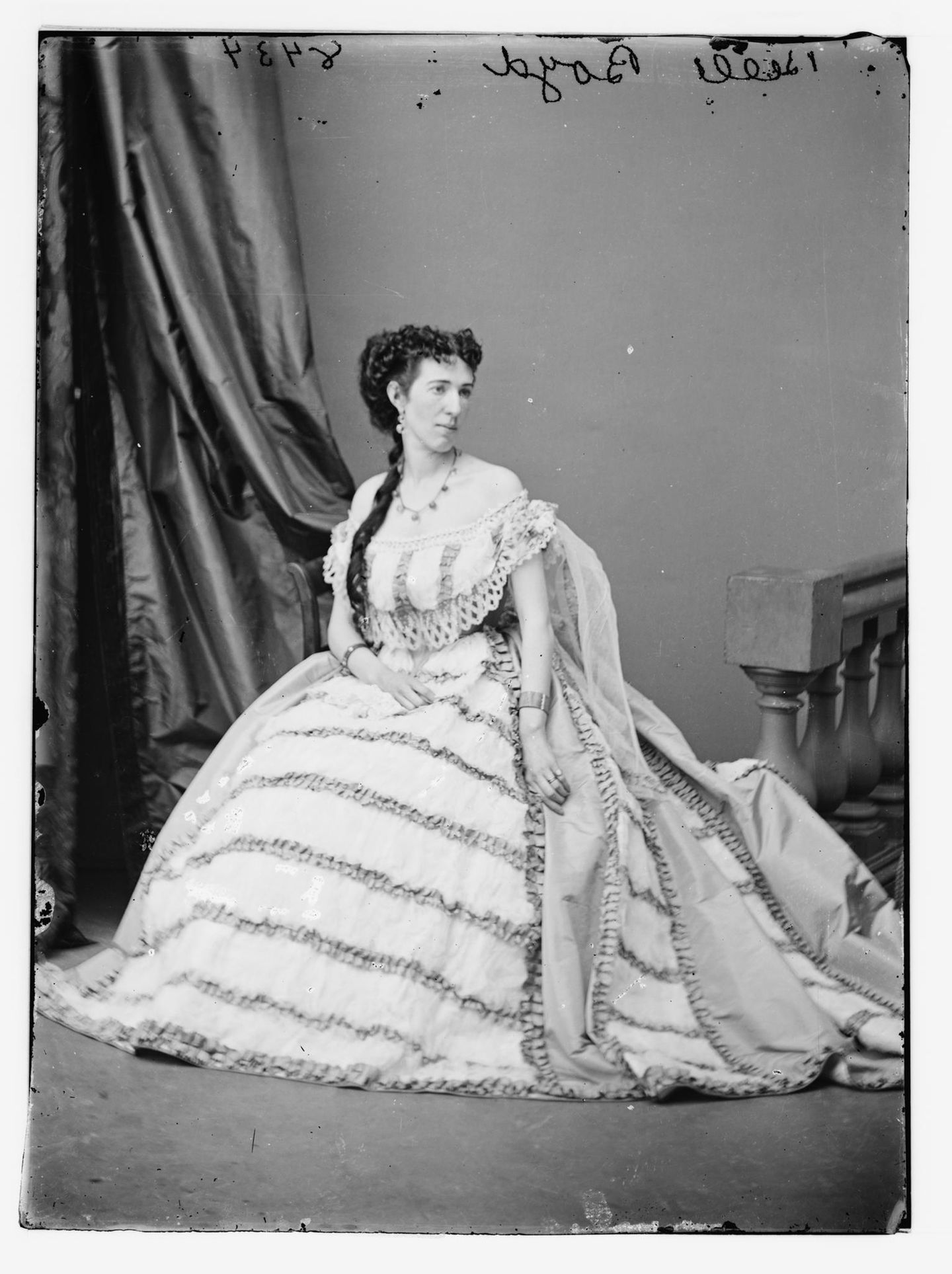 Isabelle "Belle" Boyd (1844–1900) – La Belle Rebelle Ganzkörperporträtfoto einer sitzenden Frau in hellem Rüschengewand, mit Schärpe und kunstvoller Frisur, um 1860