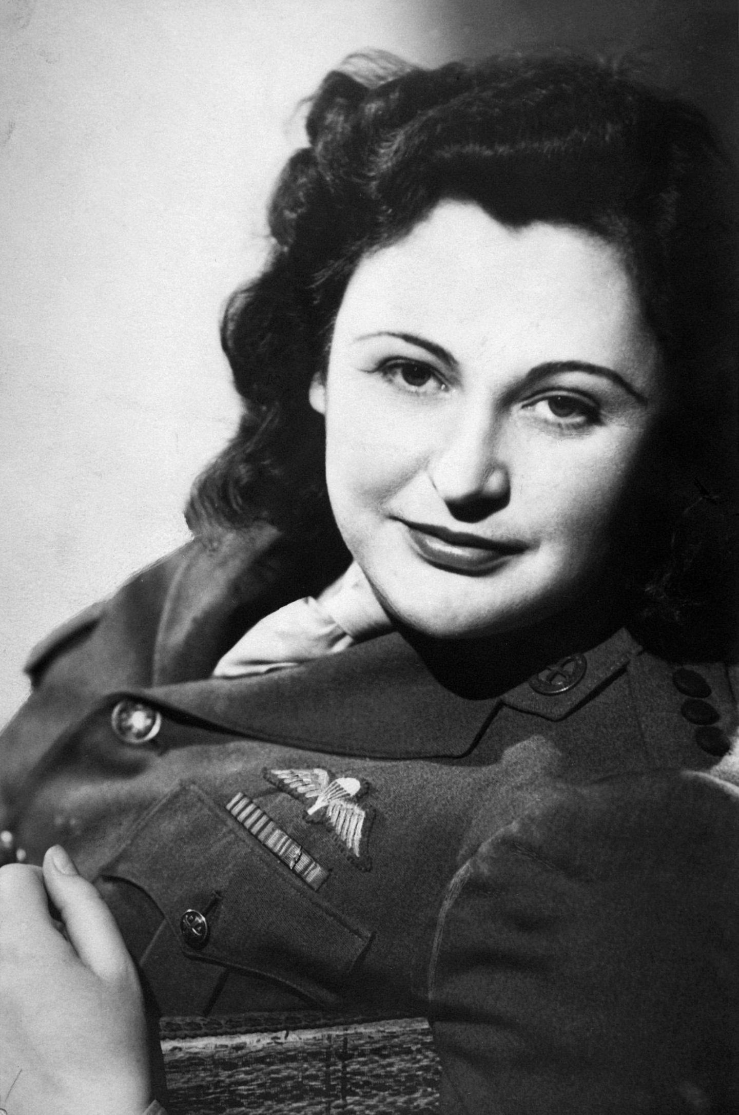 Porträtfoto einer Frau in Uniform mit offenen dunklen Haaren, schwarz-weiß, 1945