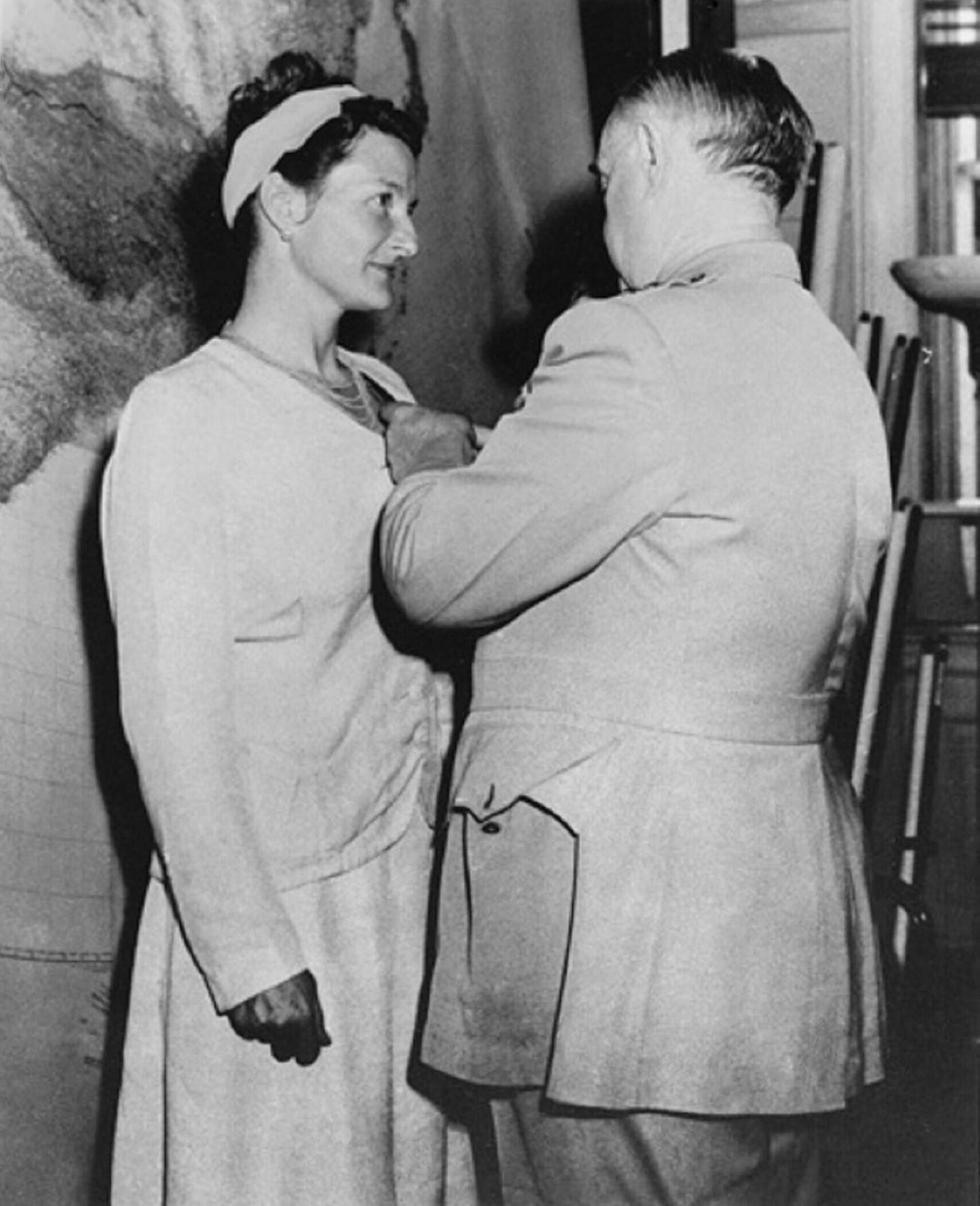 Virginia Hall (1906–1982) – Amerikas Topagentin in Frankreich Ein Mann steckt einer Frau in Kleid und mit hellem Haarband einen Orden an, schwarz-weiß, 1945