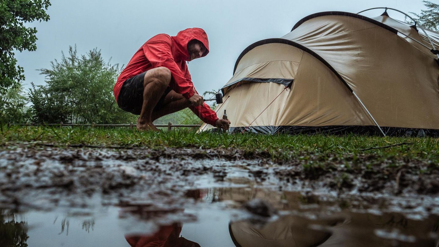 Mann baut Zelt bei Gewitter auf