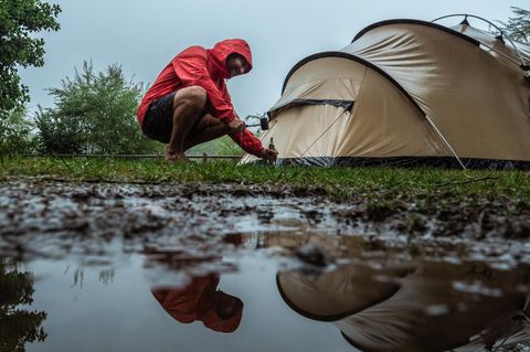 Mann baut Zelt bei Gewitter auf