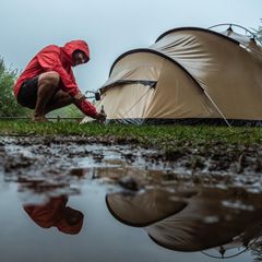 Mann baut Zelt bei Gewitter auf