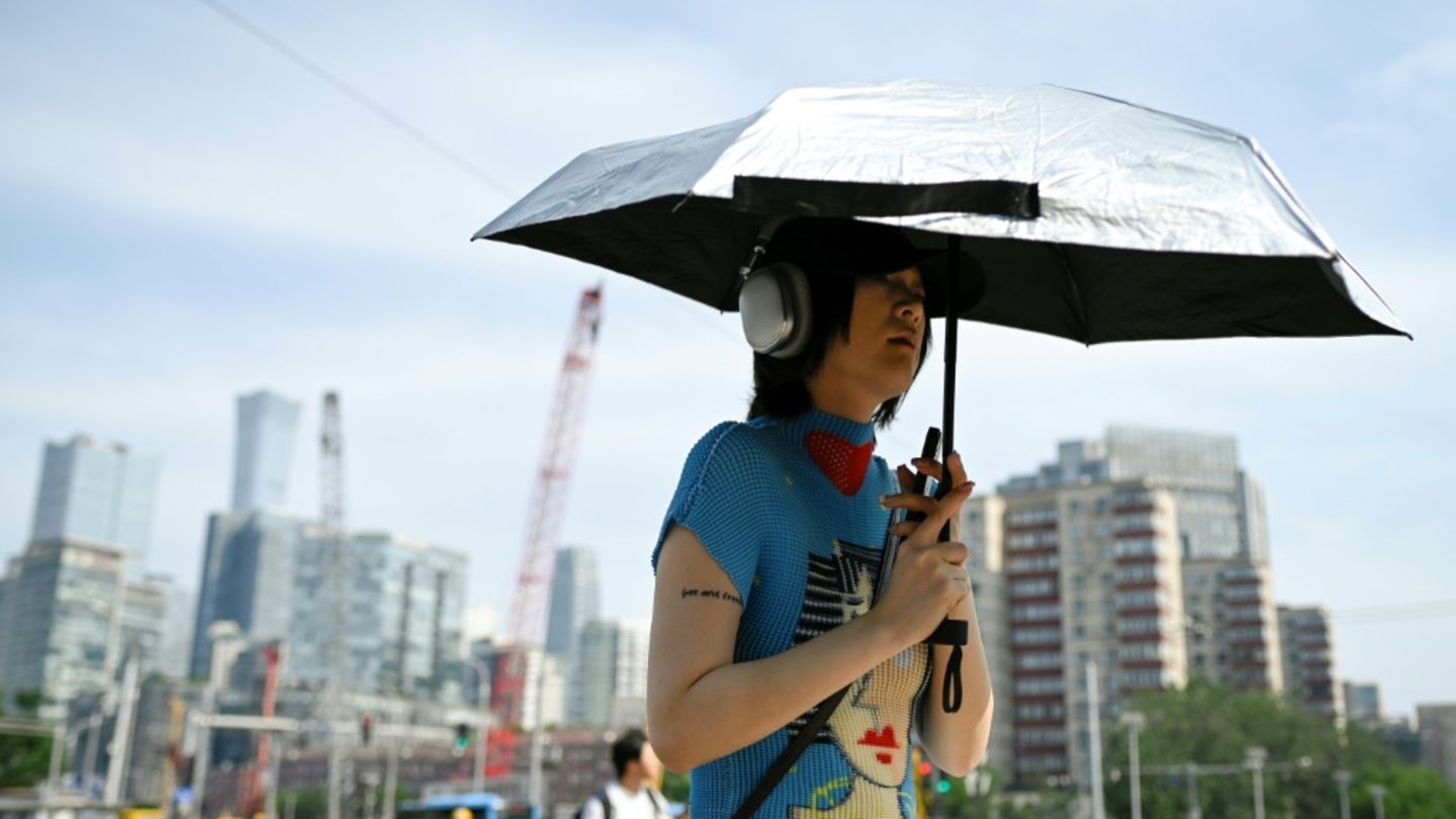 Einwohner schützen sich mit Schirmen vor der Sonne