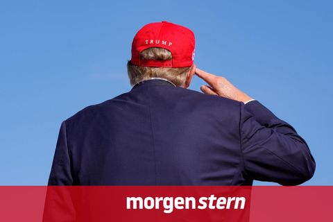Donald Trump steht mit dem Rpcken zur Kamera und salutiert