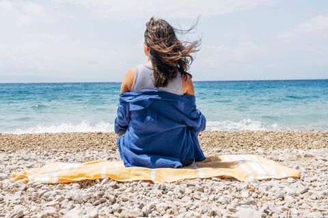 Symbolfoto für Single: Eine Frau sitzt alleine am Strand