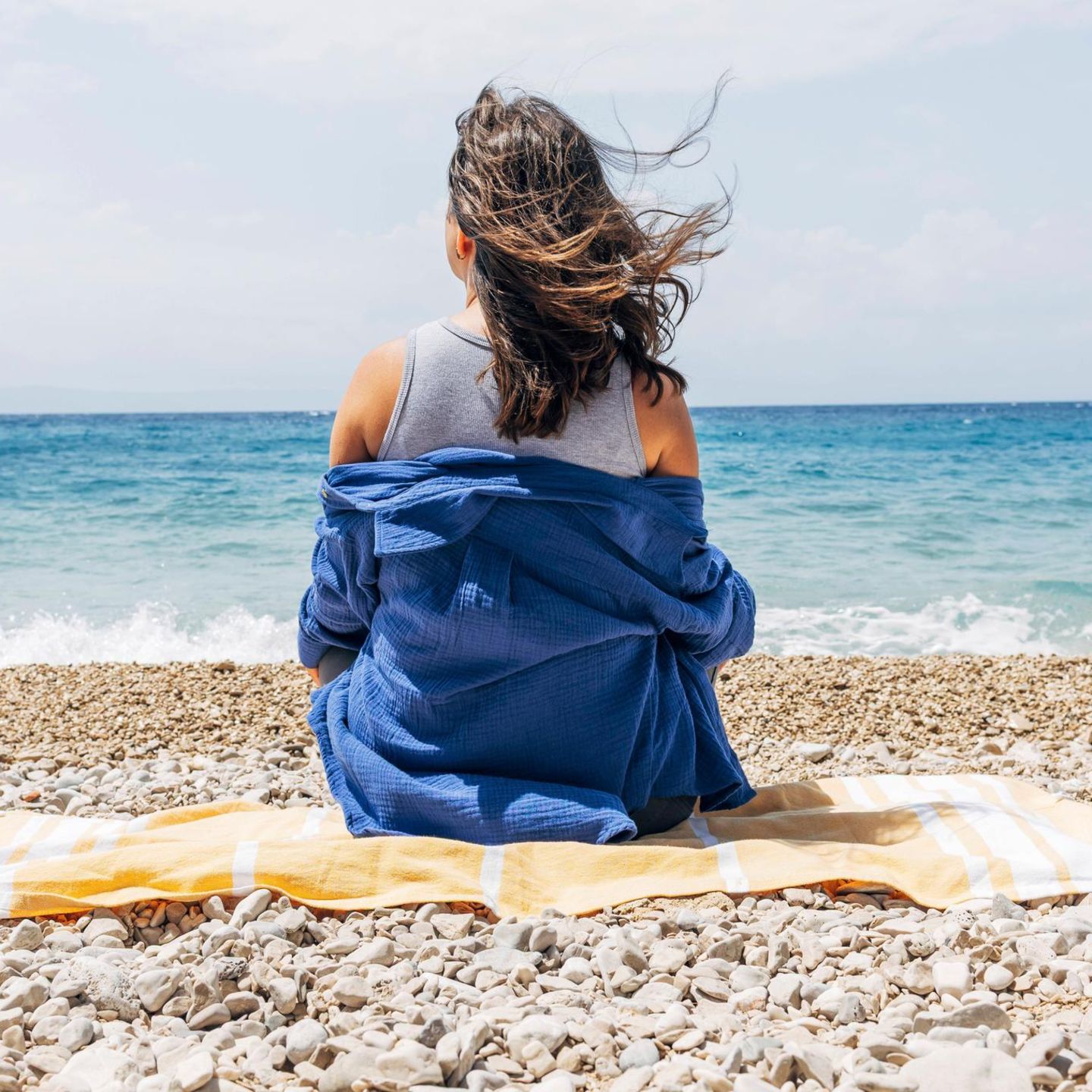 Symbolfoto für Single: Eine Frau sitzt alleine am Strand