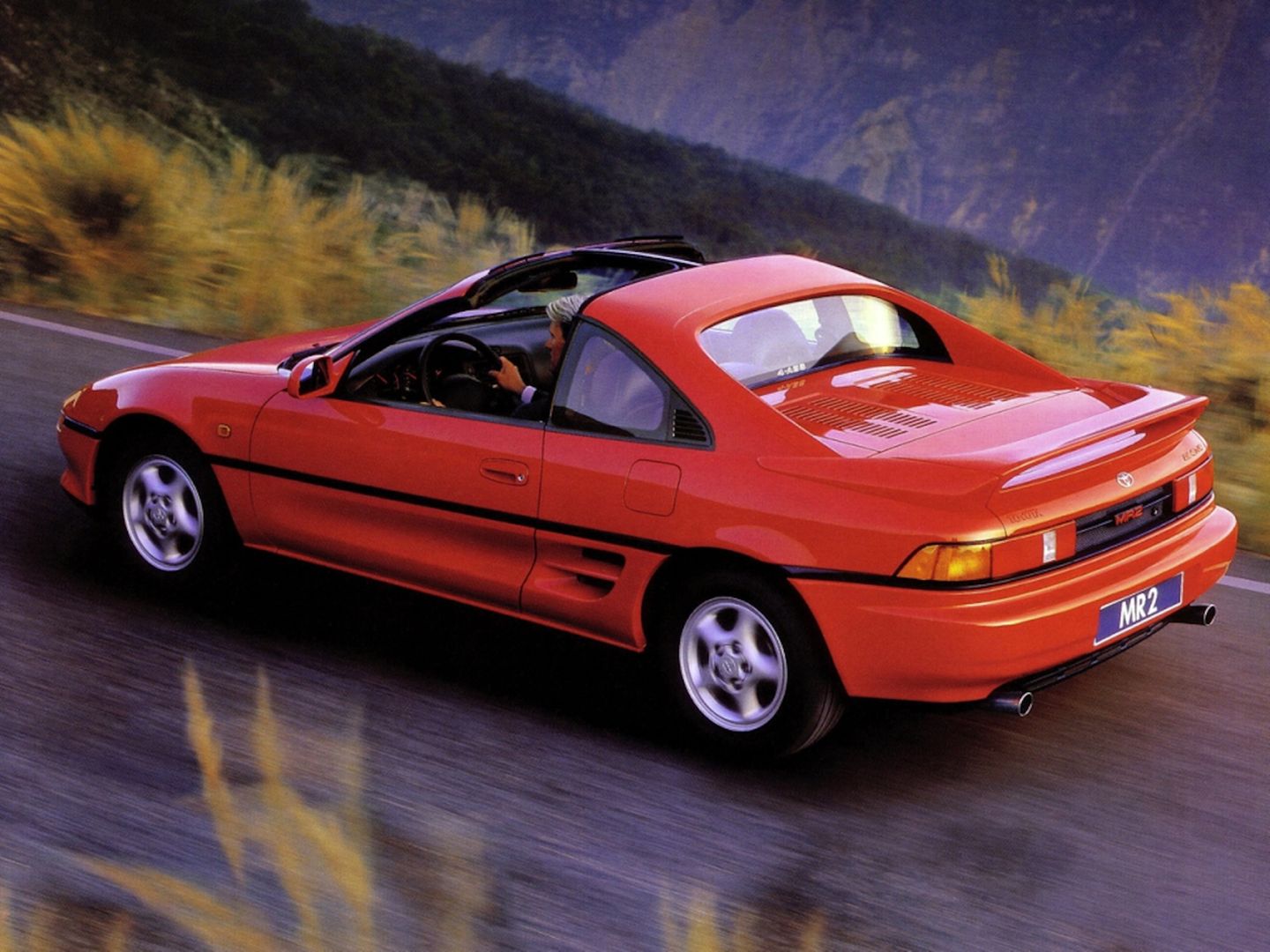 Ein roter Toyota MR2 fährt über eine Landstraße Ein roter Toyota MR2 fährt über eine Landstraße