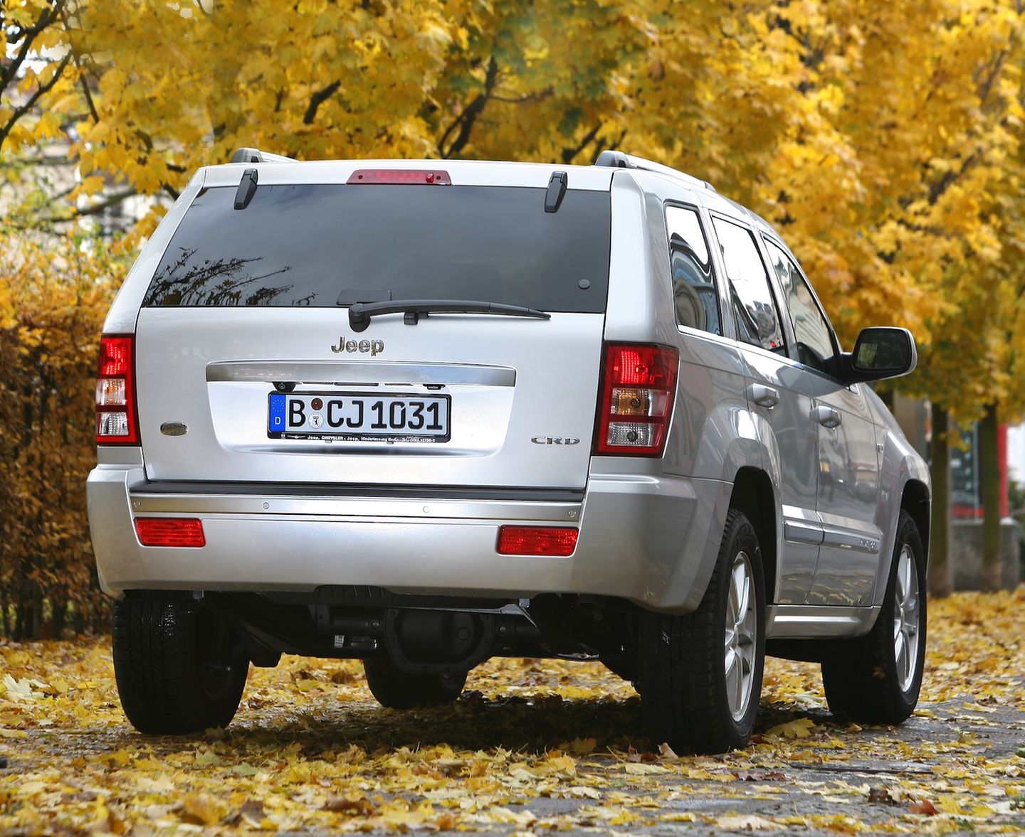 Der Jeep Grand Cherokee fährt über eine Straße mit viel Laub Der Jeep Grand Cherokee fährt über eine Straße mit viel Laub