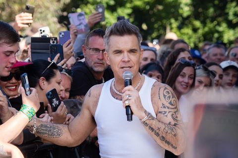 Robbie Williams schüttelt Hände in Melbourne, Australien. Er trägt ein weißes Achselhemd