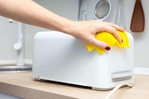 Person beim Toaster-Reinigen
