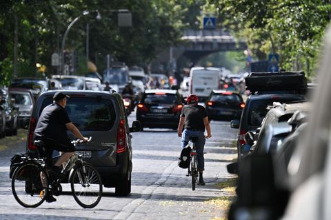 Fahrradfahrer und Autos schlängeln sich durch eine schmale Straße mitten in Berlin
