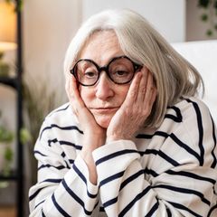 Symbolfoto für Single: Eine Frau sitzt alleine in einem Wohnzimmer