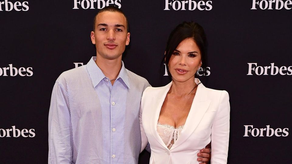 Lauren Sanchez in einem weißen Anzug mit einer tiefen Spaltung, neben ihrem Sohn Tony im hellblauen Hemd