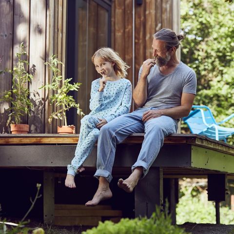 Das Haus kaufen oder lieber mieten? Vater sitzt mit Tochter auf der eigenen Veranda