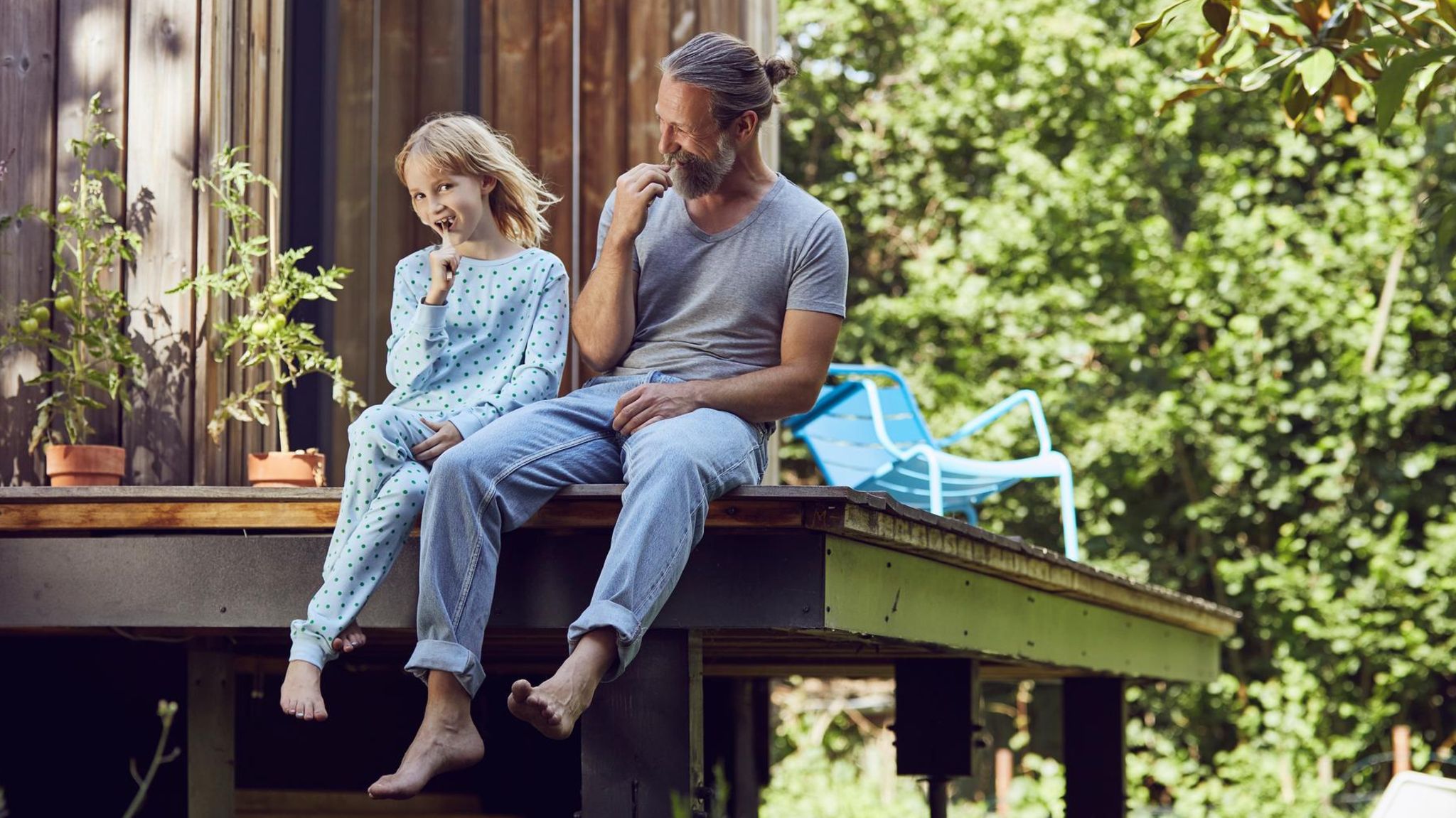 Das Haus kaufen oder lieber mieten? Vater sitzt mit Tochter auf der eigenen Veranda
