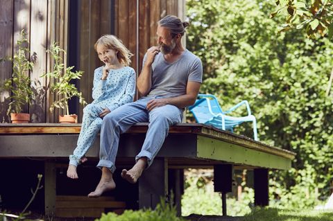 Das Haus kaufen oder lieber mieten? Vater sitzt mit Tochter auf der eigenen Veranda