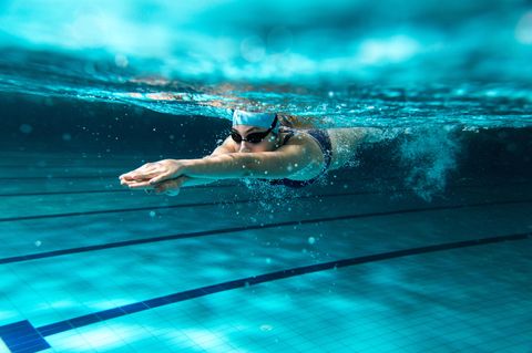 Bewegung: Frau schwimmt unterwasser mit Badekappe und Schwimmbrille