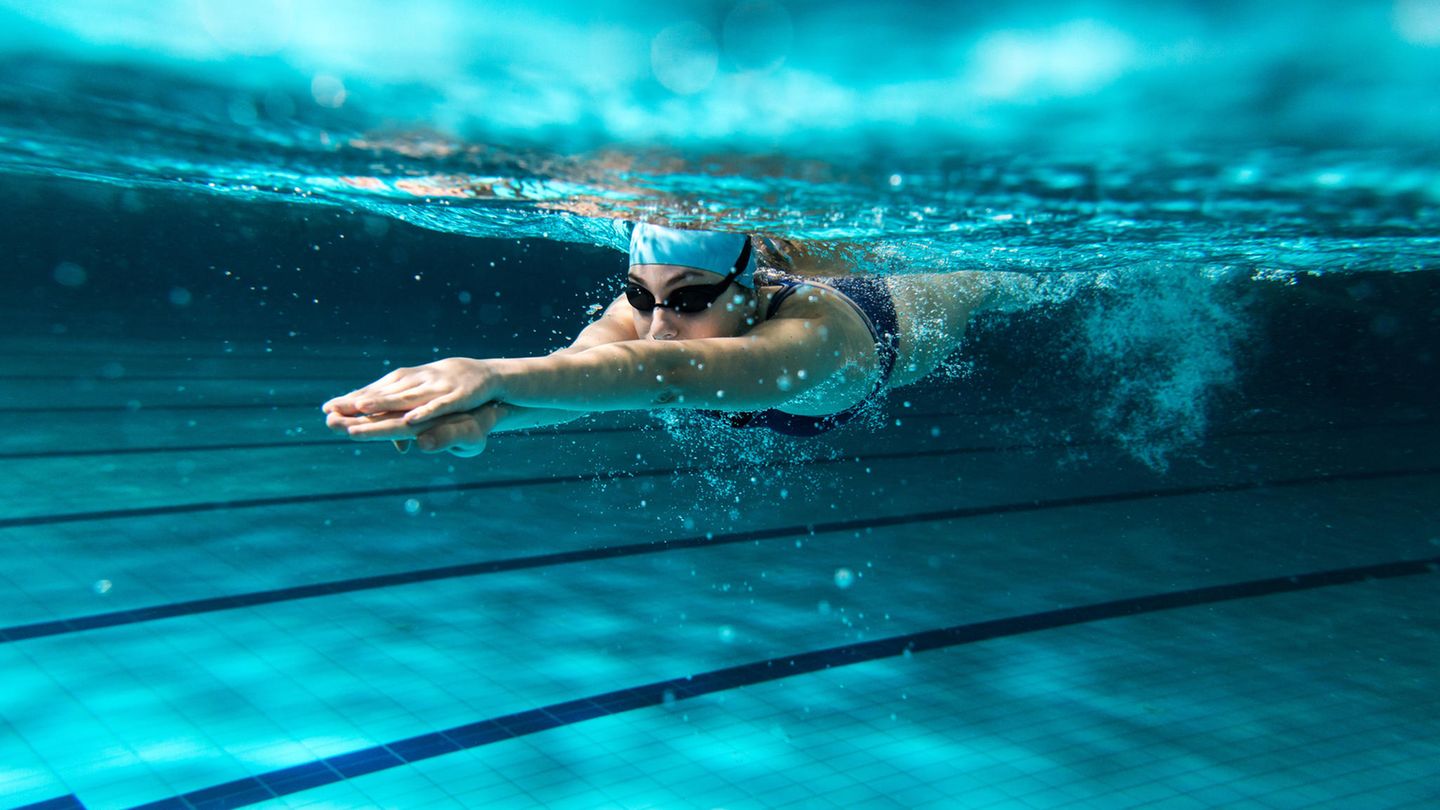 Bewegung: Frau schwimmt unterwasser mit Badekappe und Schwimmbrille