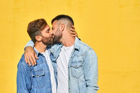 Homosexualität: Schwules Pärchen küsst sich vor einer gelben Wand