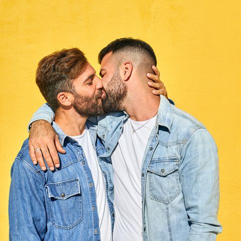 Homosexualität: Schwules Pärchen küsst sich vor einer gelben Wand