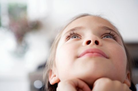 Kinder: Ein Mädchen blickt verträumt in den Himmel