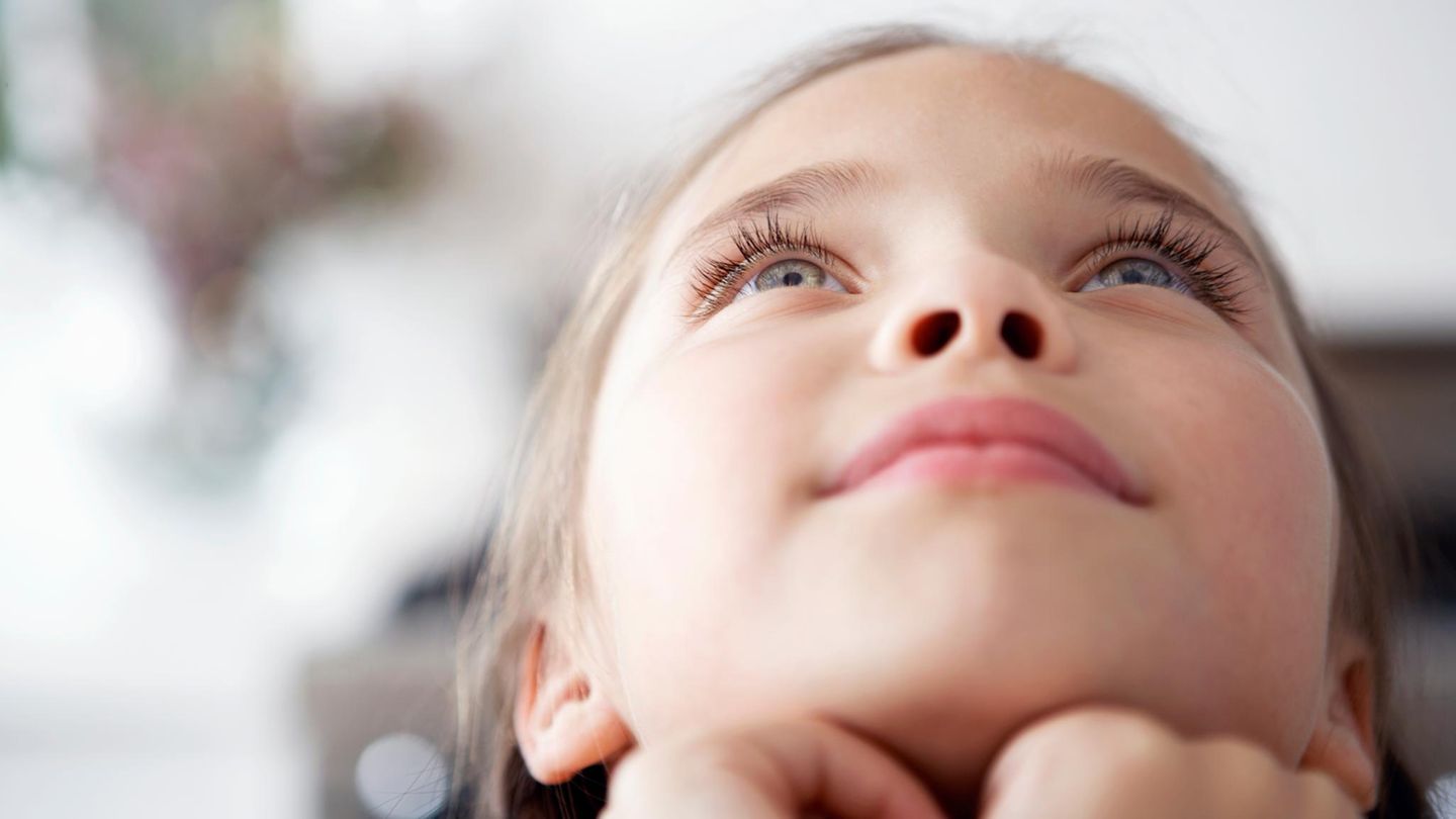 Kinder: Ein Mädchen blickt verträumt in den Himmel