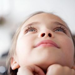 Kinder: Ein Mädchen blickt verträumt in den Himmel