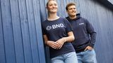 In einem Werbefoto trägt eine Frau ein BND-Shirt, ein Mann einen BND-Hoodie