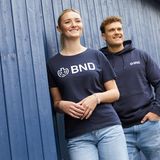 In einem Werbefoto trägt eine Frau ein BND-Shirt, ein Mann einen BND-Hoodie