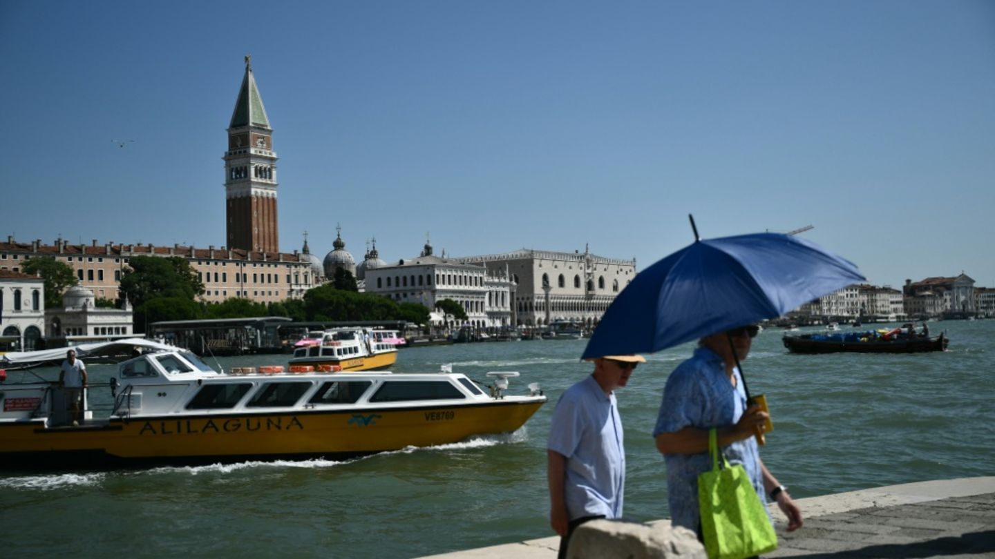 Mann schützt sich in Venedig mit Schirm vor der Sonne