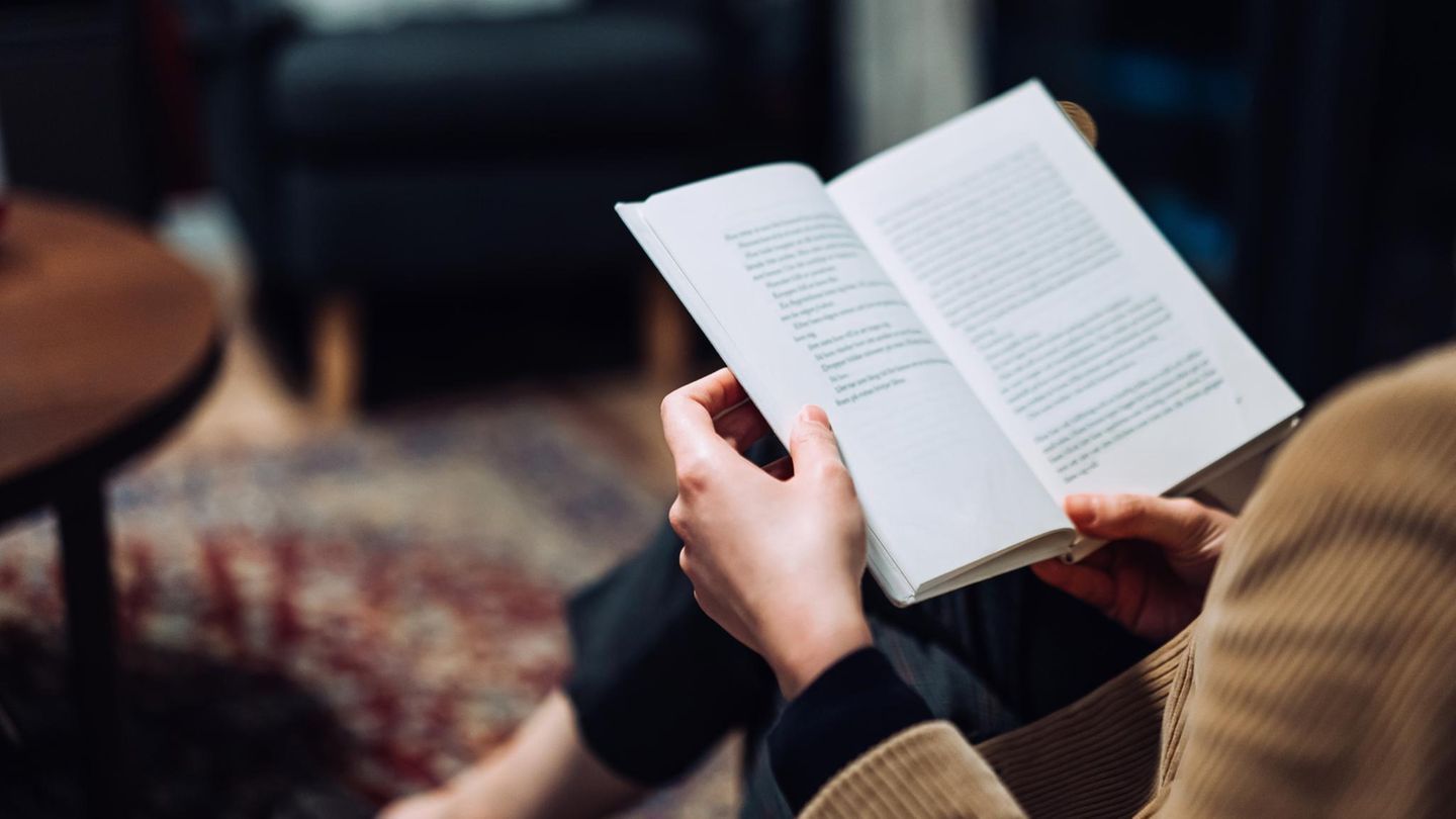 Eine Frau liest ein Buch auf dem Sofa