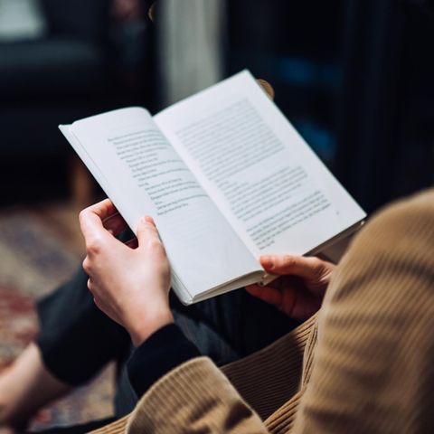 Eine Frau liest ein Buch auf dem Sofa