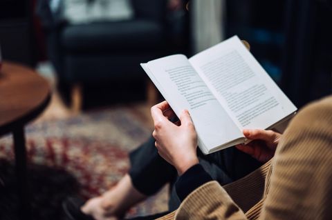 Eine Frau liest ein Buch auf dem Sofa