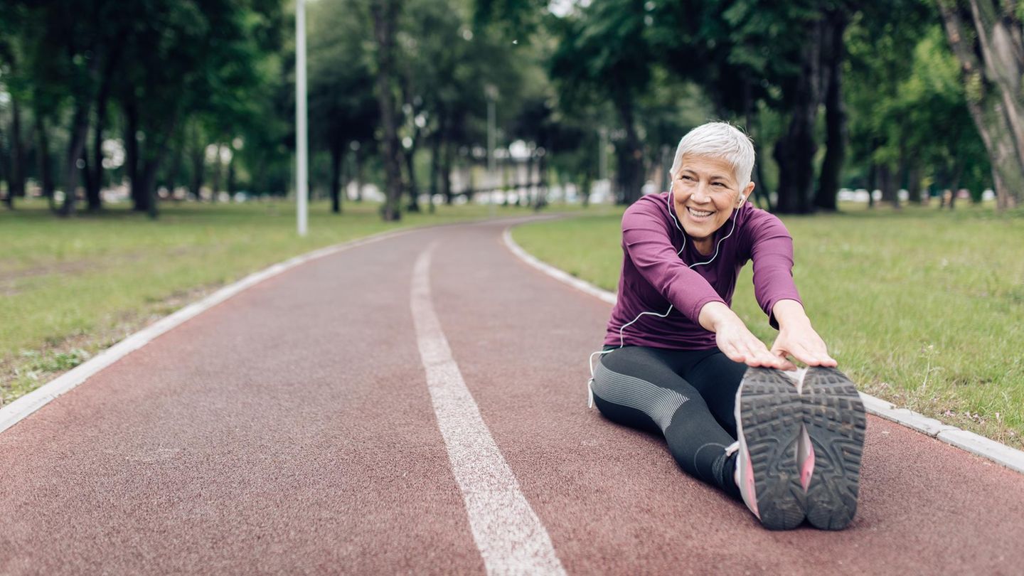 Ältere Frau in Sportkleidung beim Stretching auf einem Sportplatz